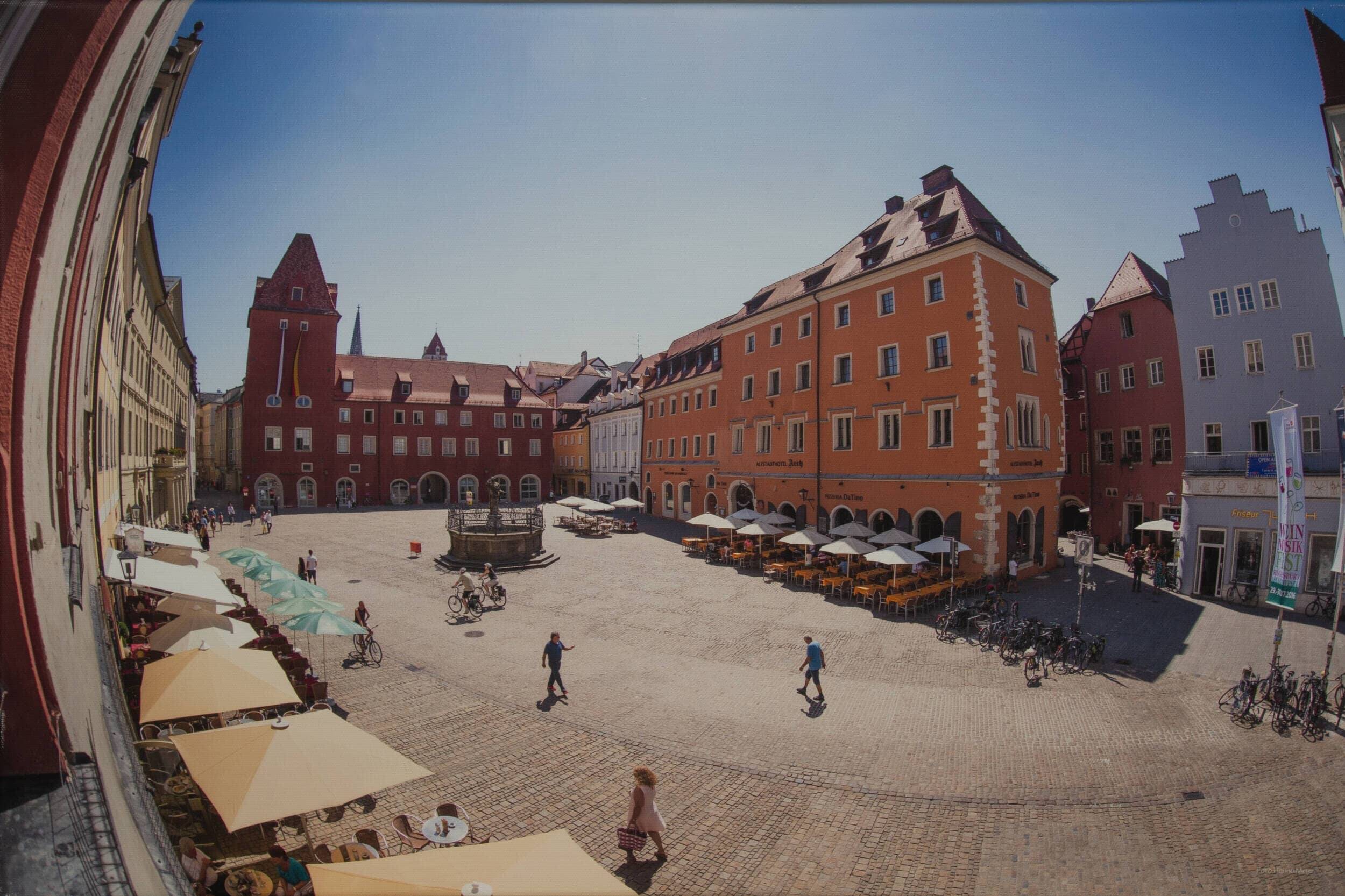 Historischer Marktplatz mit bunten Gebäuden und Cafés im Freien, ideal für einen entspannten Tag in der Stadt.