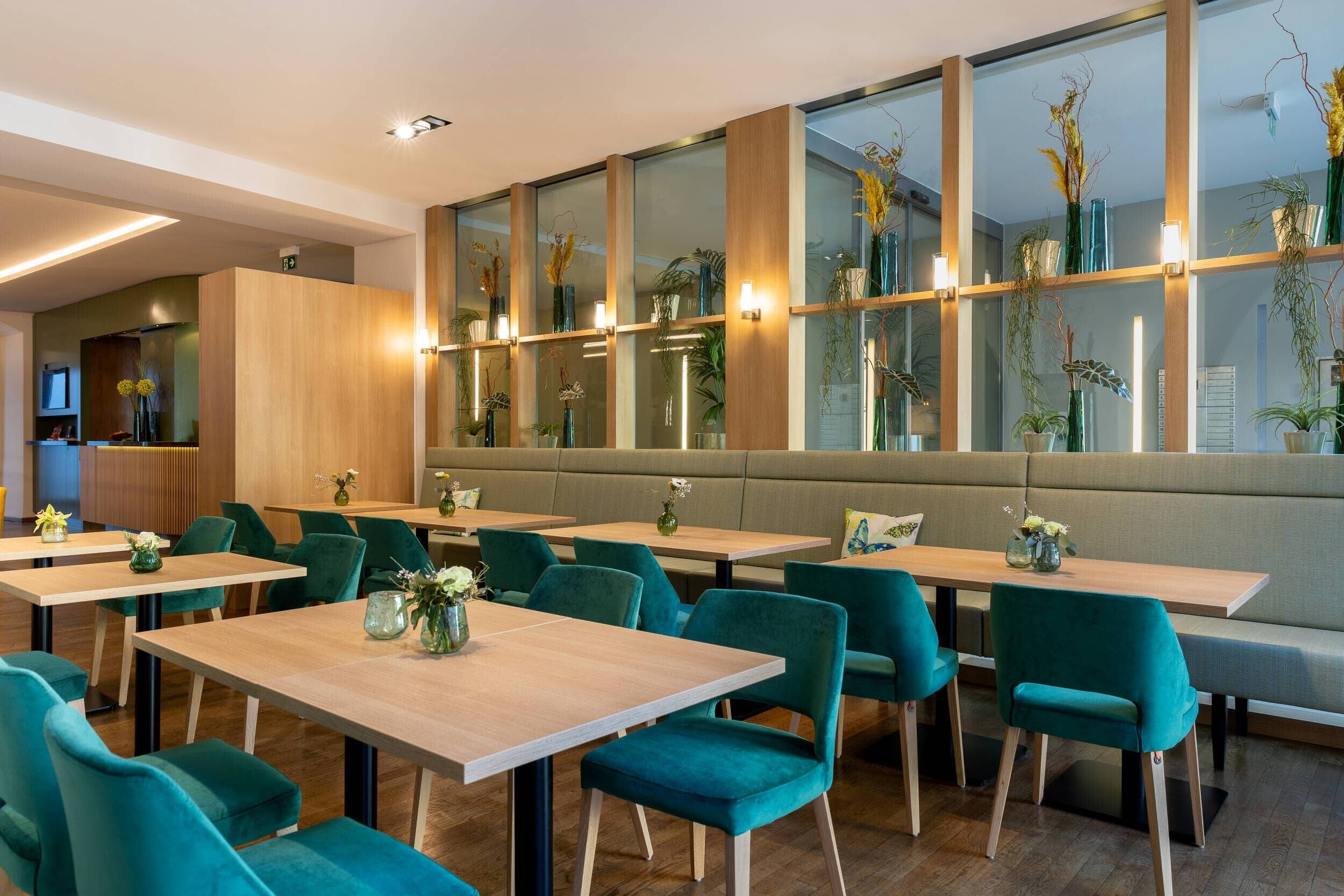 Das moderne Restaurant bietet stilvolle grüne Stühle und Holz-Esstische, ideal für entspannte Familienessen im Hotel.